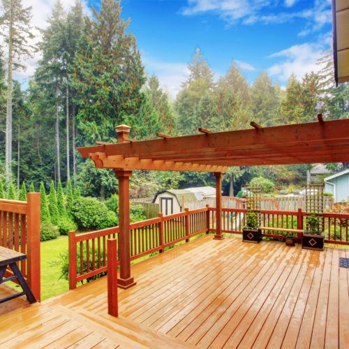 Spacious wooden deck with benches and attached pergola